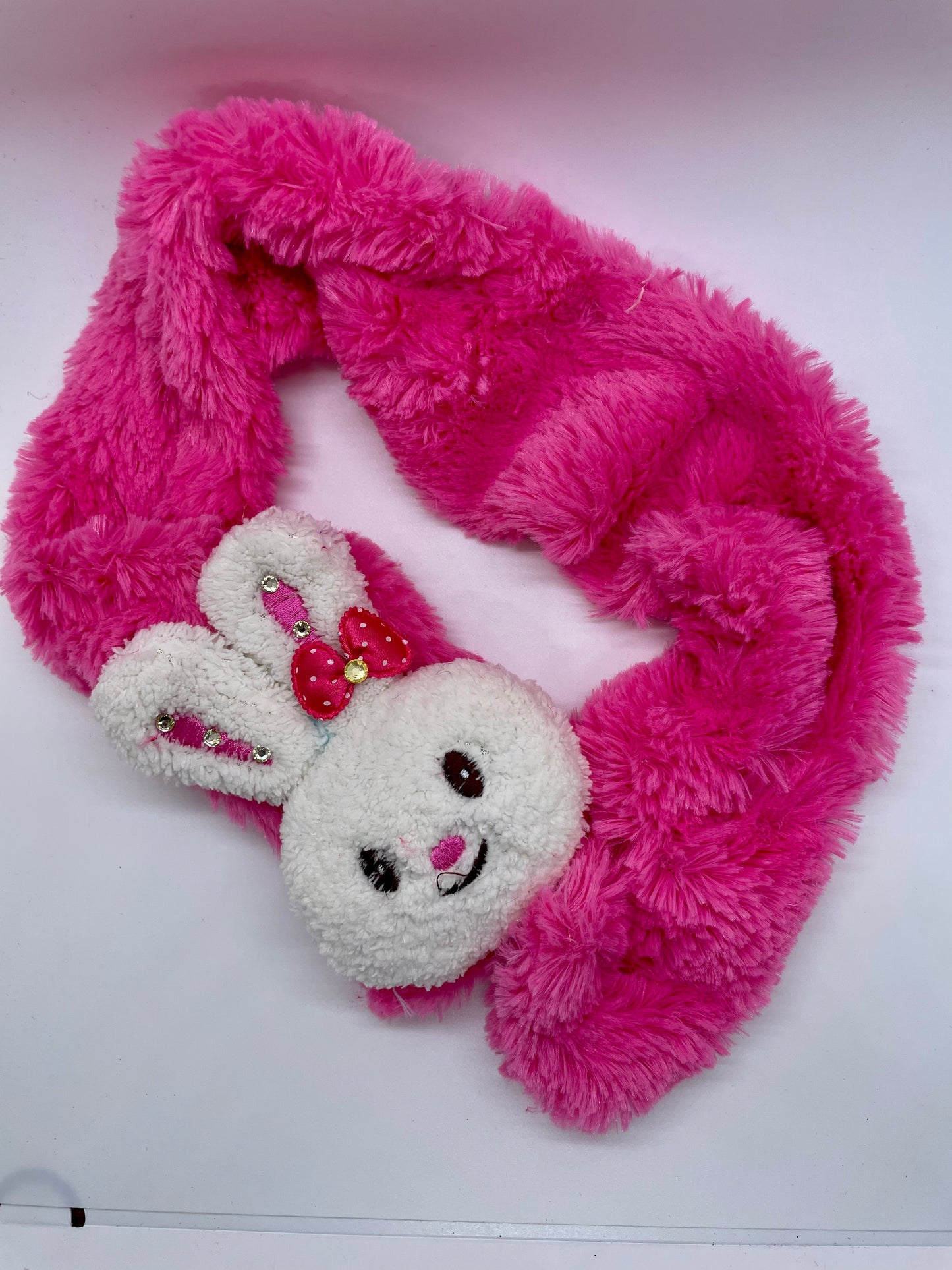 "Pink kid's scarf with a knit flower detail and a fold-over cuff"