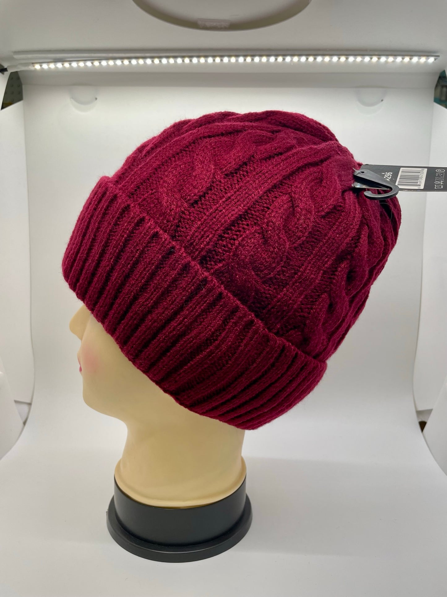 "Red knitted beanie with a cable knit pattern and a fringed edge"